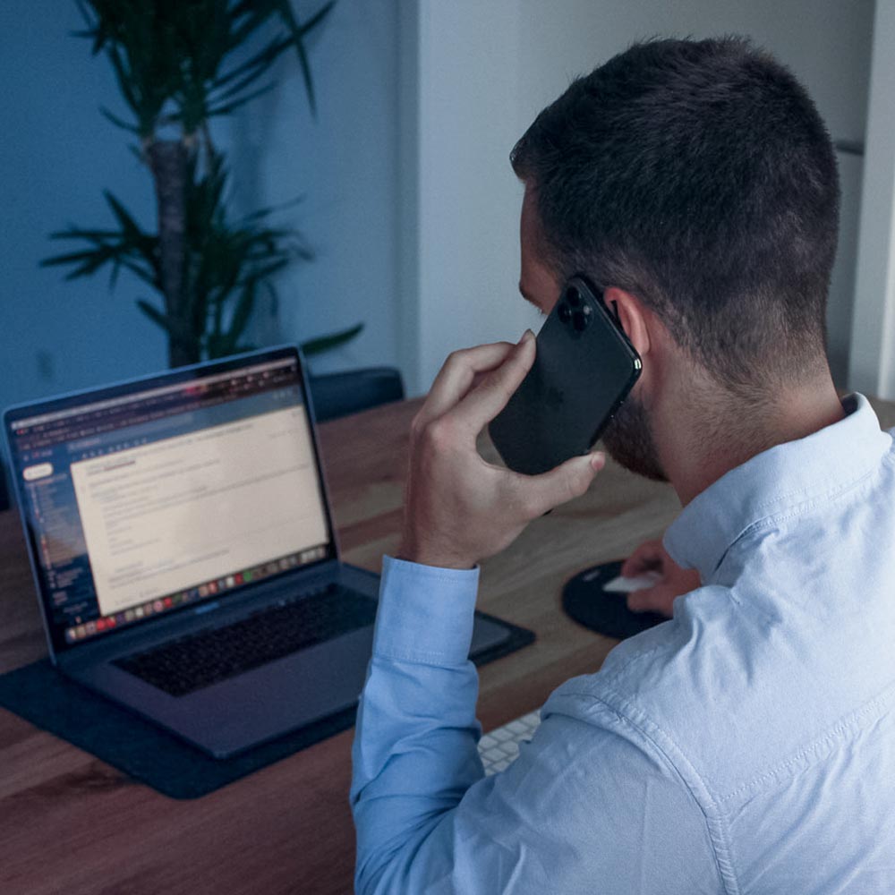 man talking on phone while using laptop